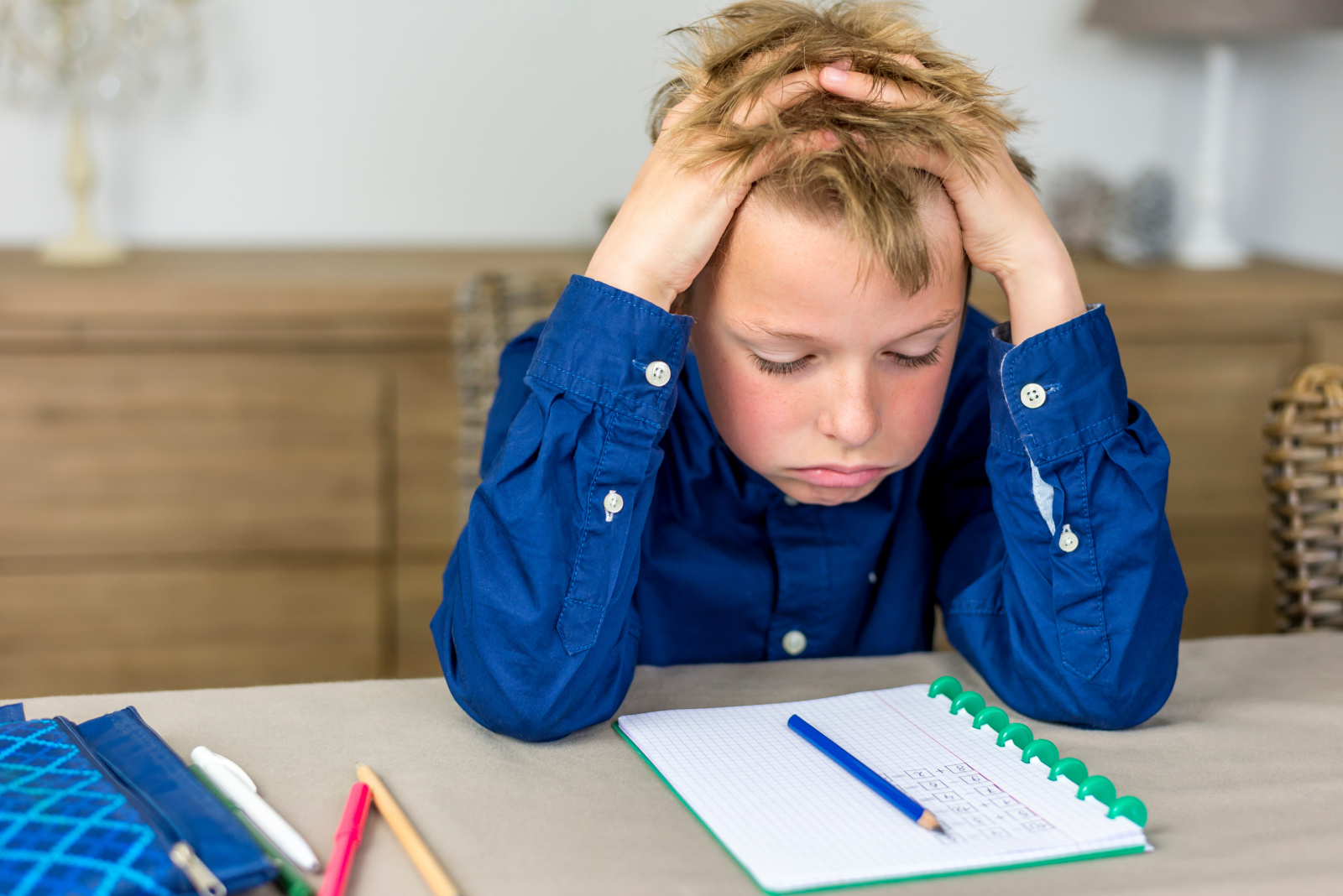 boy struggling with his homework, holding his hands in his hair